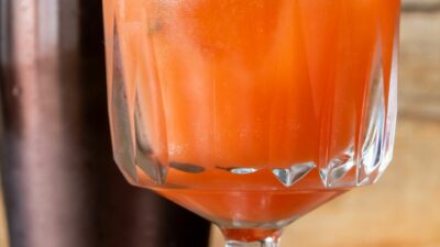 A belmont breeze cocktail in a glass with a shaker behind it