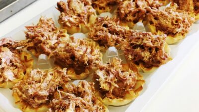 Pork side bites in mini phyllo cups on a serving tray.