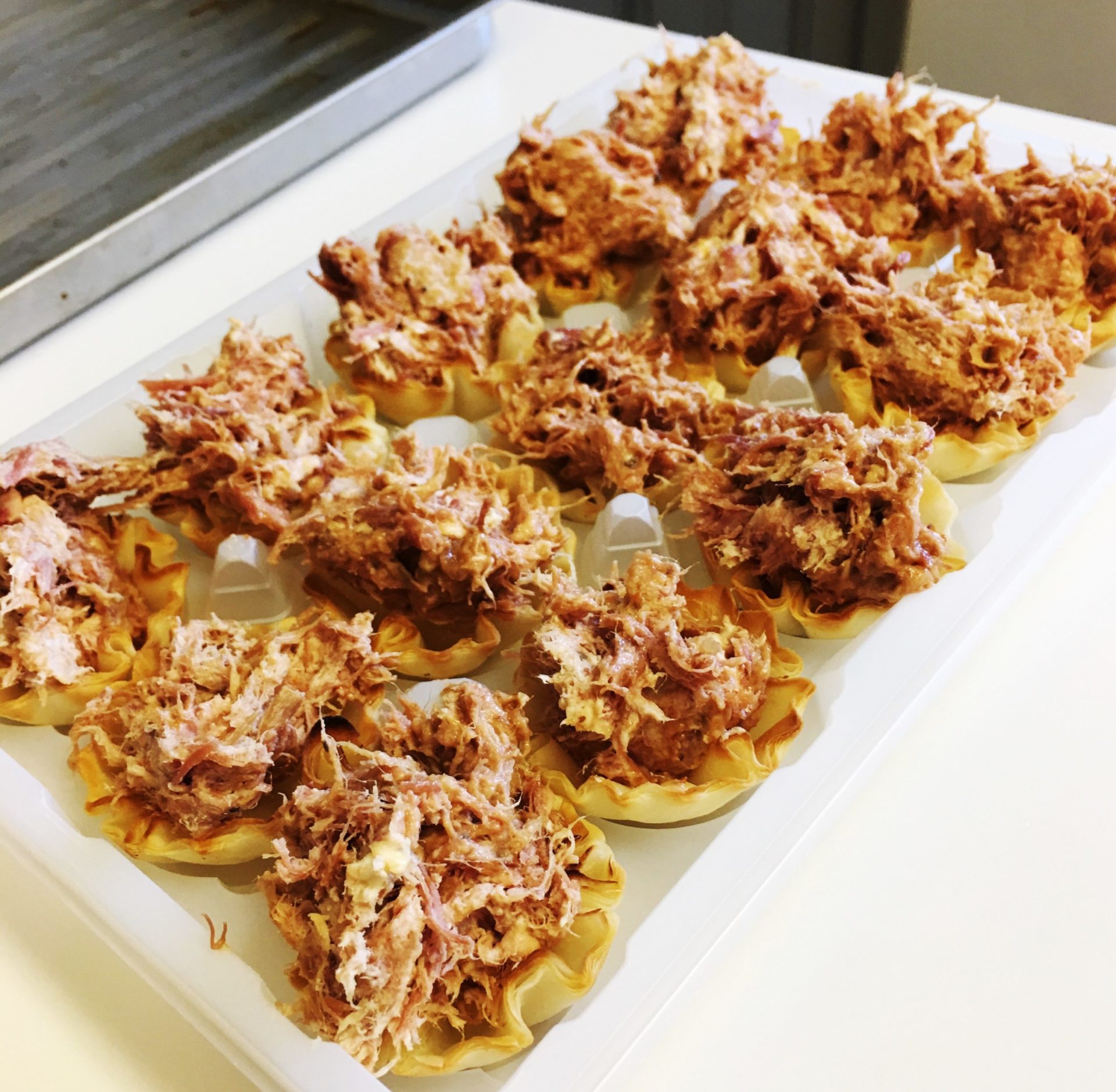 Pork side bites in mini phyllo cups on a serving tray.