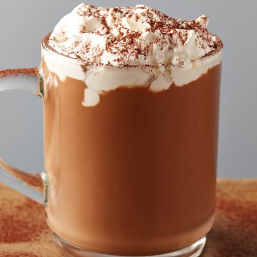 Tequila hot chocolate in a glass mug topped with whipped cream and cinnamon