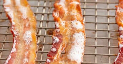 Strips of candied bacon on a wire rack baking in the oven