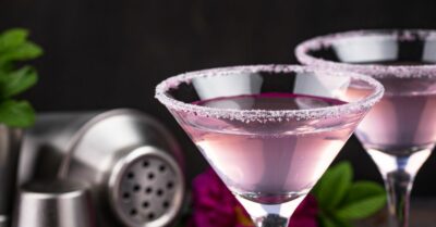 A light purple eagle cocktail in a martini glass with a black background