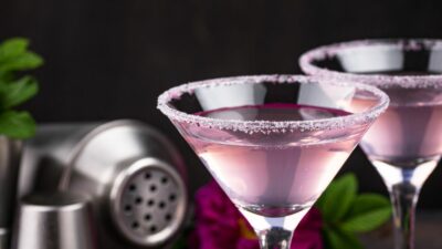 A light purple eagle cocktail in a martini glass with a black background
