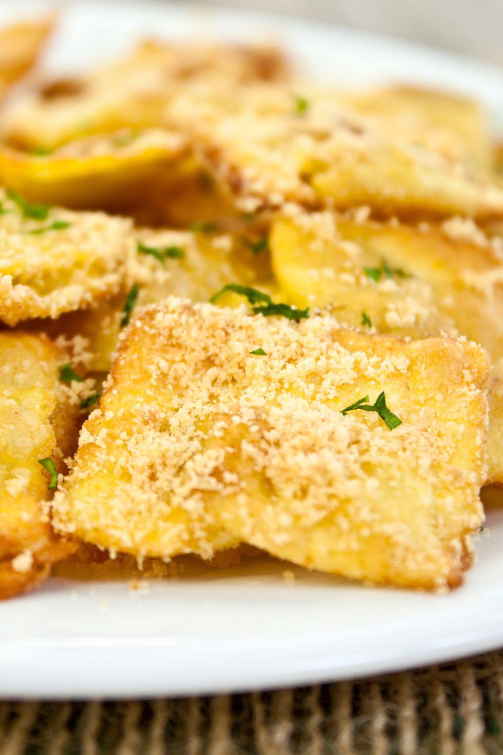 Golden fried ravioli sprinkled with parmesan cheese on a white plate