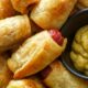 pull apart pigs in a blanket in a pile with mustard next to it