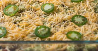 Race day dip in a glass baking dish topped with sliced jalapeno peppers