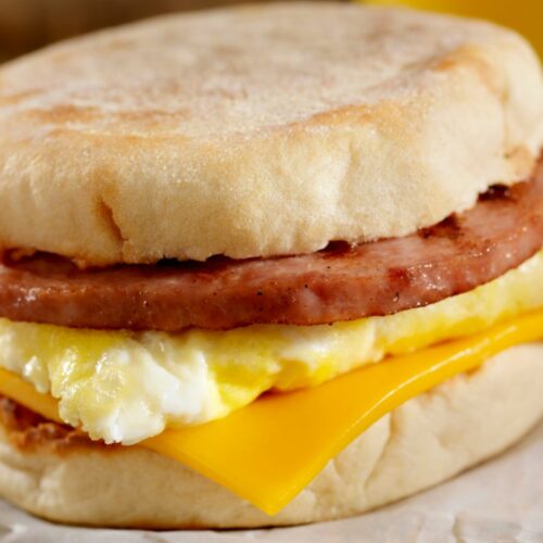 A simple egg sandwich on an english muffin with sausage and cheese