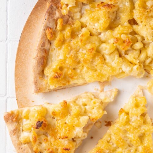 An overhead shot of bbq chicken mac' n' cheese pizza on a white surface
