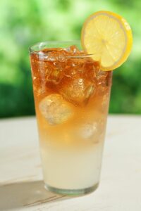 An Arnold Palmer drink in a glass with a lemon wedge
