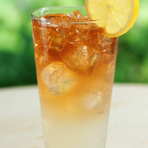 An Arnold Palmer drink in a glass with a lemon wedge