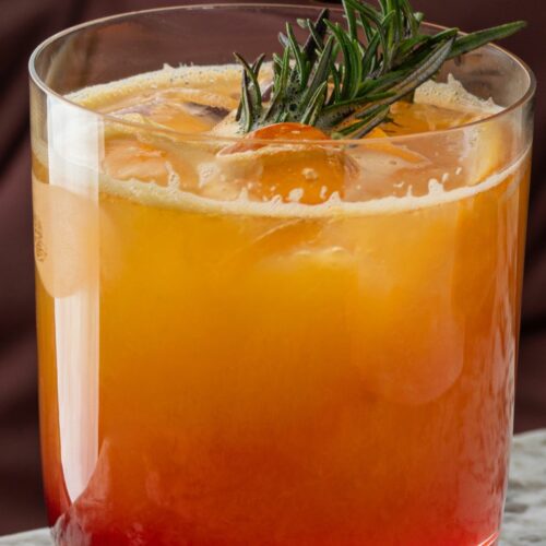 An azalia cocktail in a glass with rosemary on top