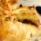 A golden wheel of baked Brie en croute filled with raspberry preserves and nuts.