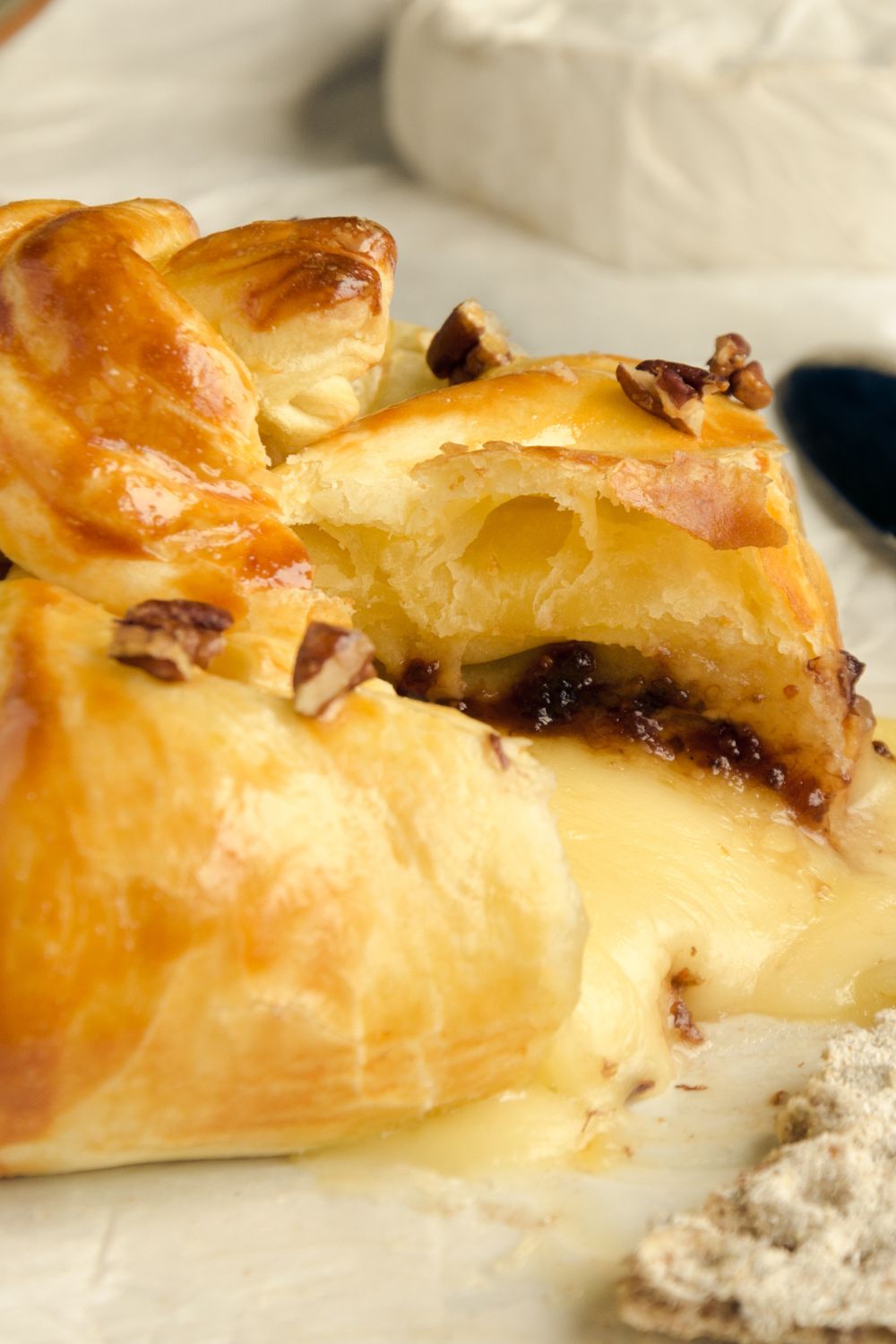 A golden wheel of baked Brie en croute filled with raspberry preserves and nuts.