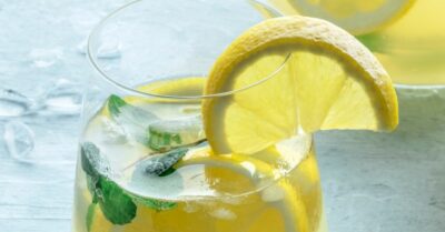 Coconut lemon punch in a glass garnished with lemon slices and mint
