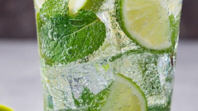 A glass filled with mojito, limes and mint leaves