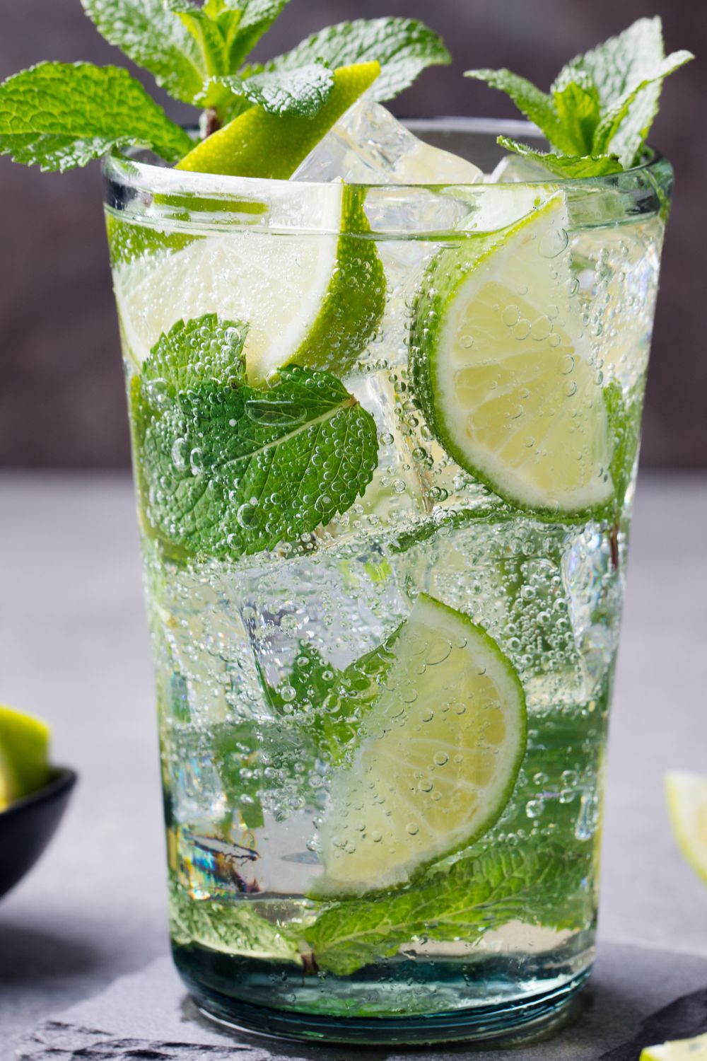 A glass filled with mojito, limes and mint leaves