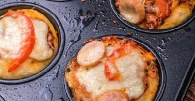 A muffin tin filled with cupcake pizzas
