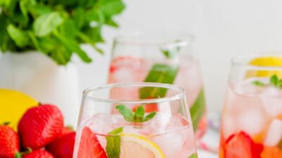 strawberry wine punch in a glass with ice, lemon slices, strawberry slices, and mint.