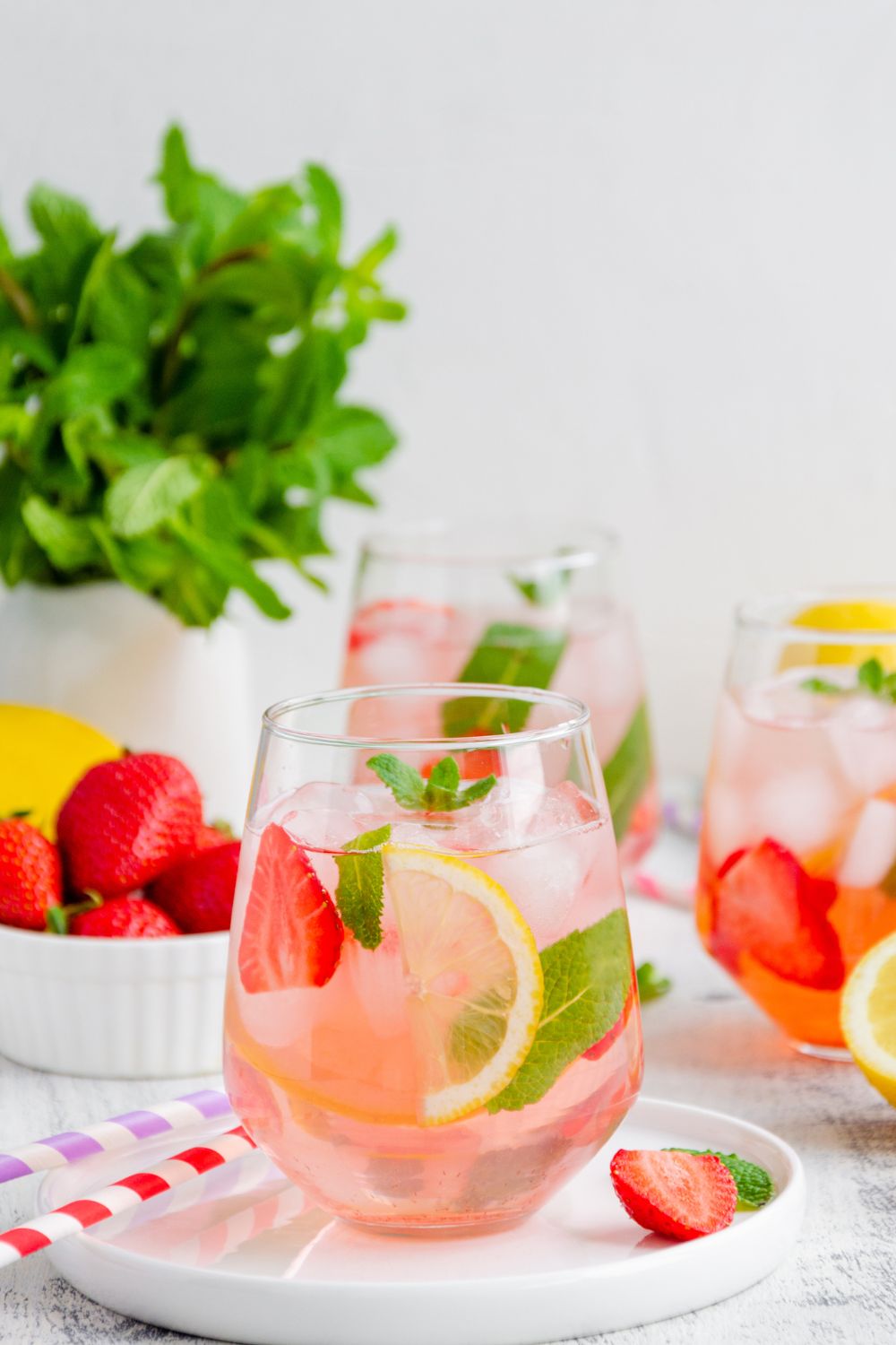 strawberry wine punch in a glass with ice, lemon slices, strawberry slices, and mint.