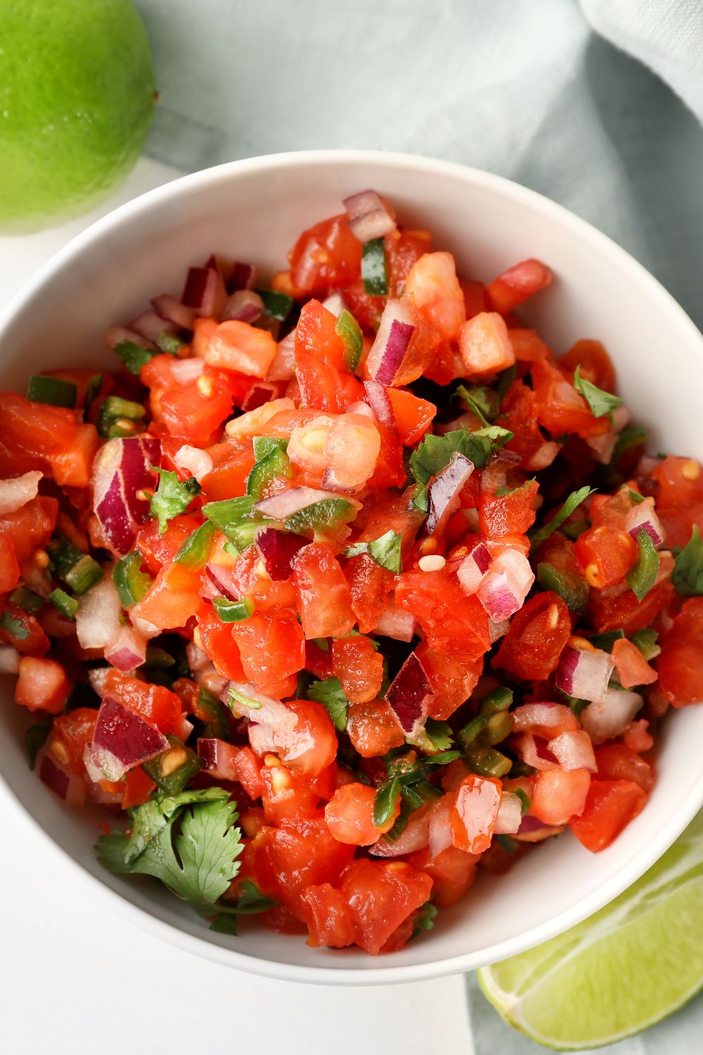 A bowl of tennis team salsa filled with chopped tomatoes red onion, and cilantro