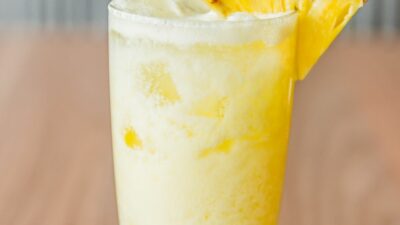 A black eyed susan cocktail in a glass with a slice of pineapple on the rim