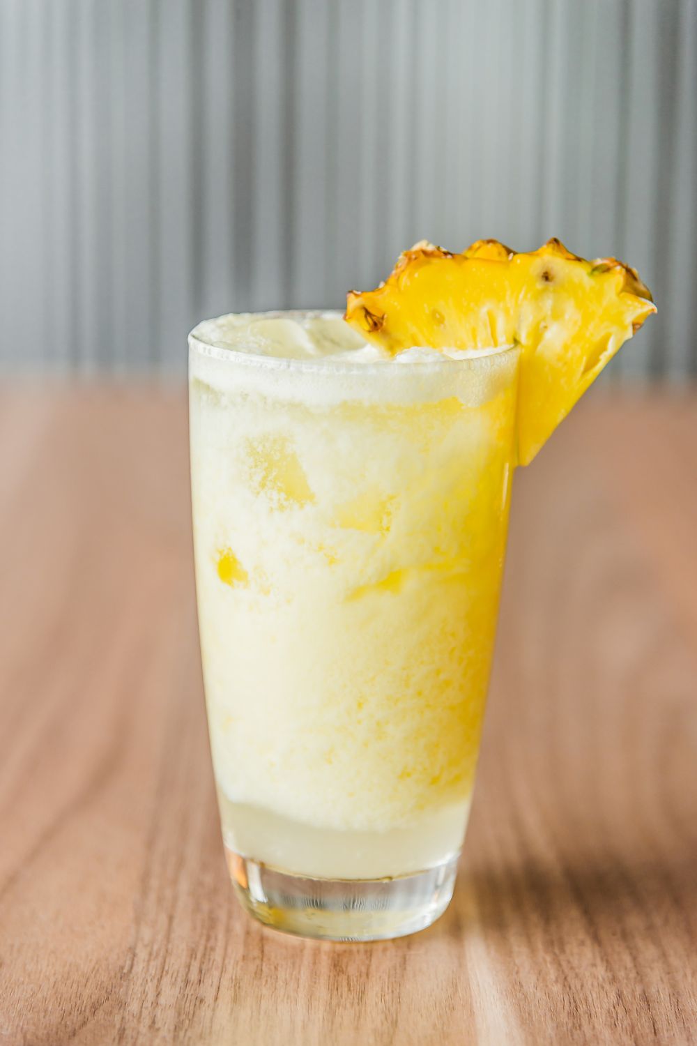A black eyed susan cocktail in a glass with a slice of pineapple on the rim
