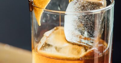 A brown derby cocktail being strained into a glass with ice