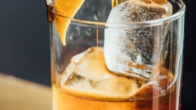 A brown derby cocktail being strained into a glass with ice
