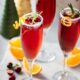Three orange cranberry bellini's in champagne flutes garnished with orange and rosemary
