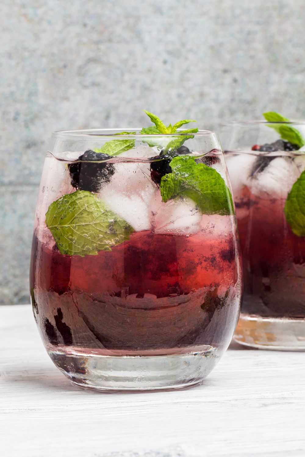 A hats off julep cocktail in a glass garnished with blackberries and mint