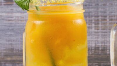 A mango mary cocktail in a glass with a celery stick