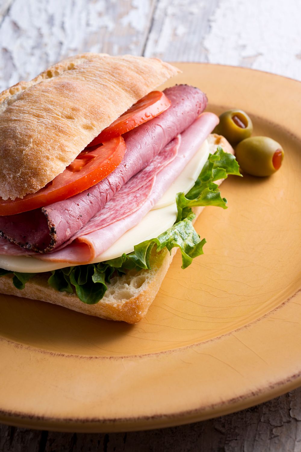 Mario Carbone's Italian sandwich on a plate with sliced tomato and lettuce