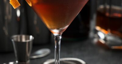 A Pimm's cup cocktail in a martini glass with an orange twist