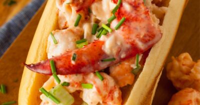 A stuffed lobster roll in between a buttery toasted bun and topped with chives