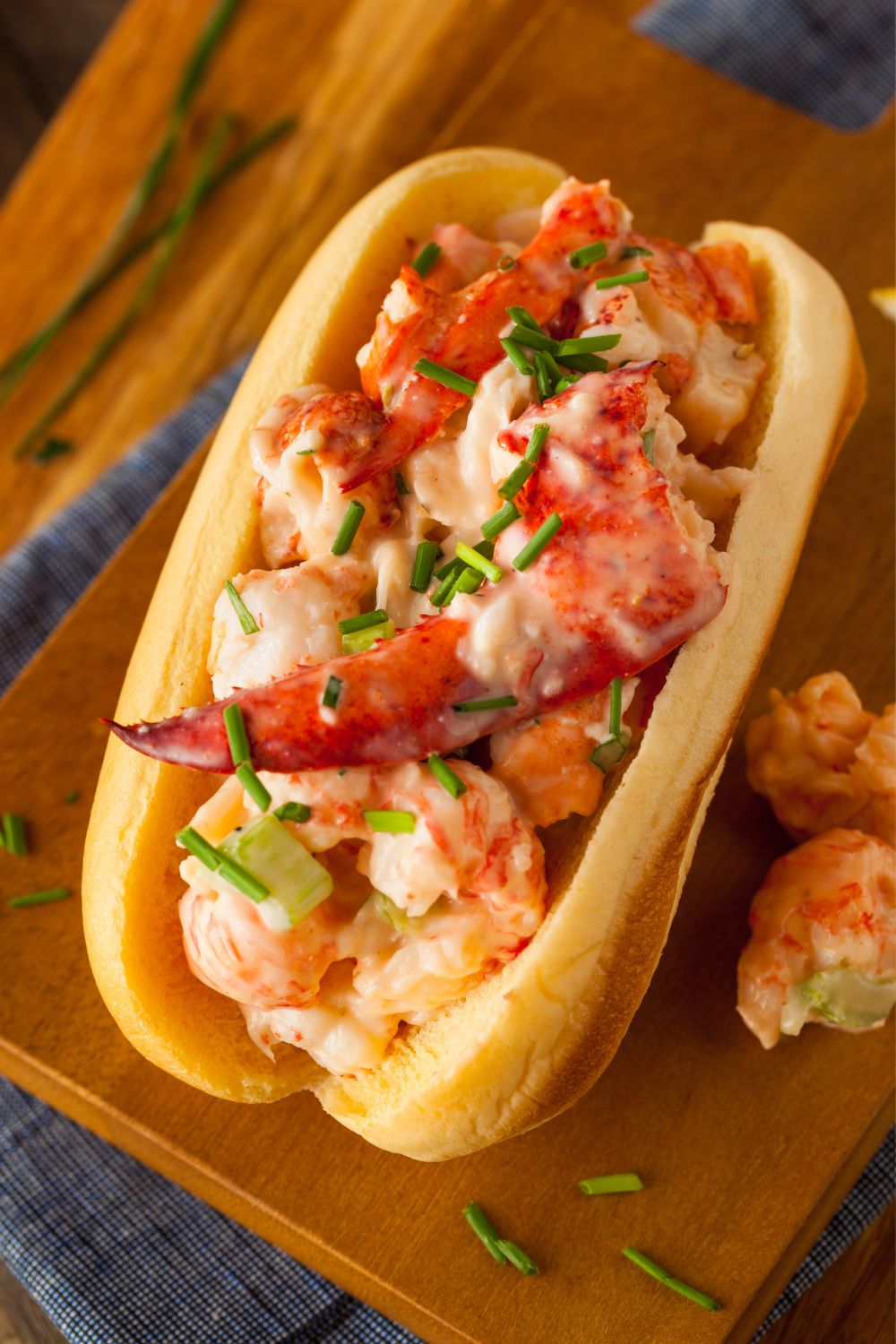 A stuffed lobster roll in between a buttery toasted bun and topped with chives