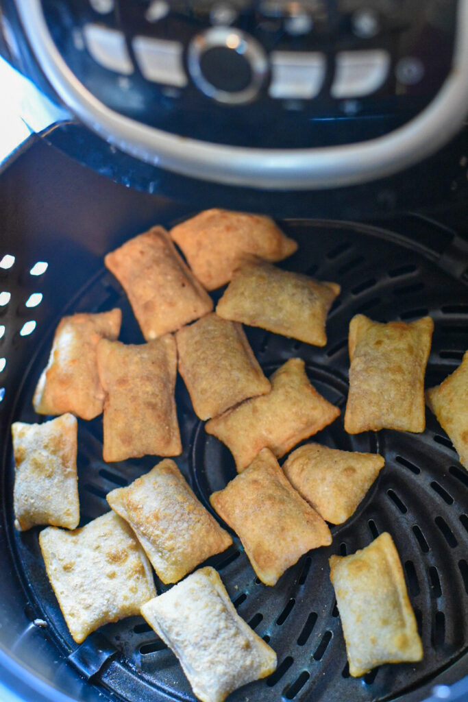 Cooked pizza rolls in an air fryer basket.