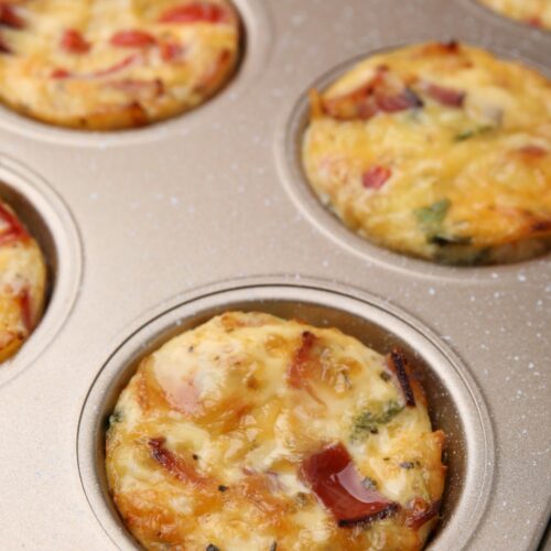 a muffin tin with grilled eggs in it
