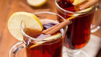A hot coffee grog in a glass garnished with cinnamon stick and lemon.
