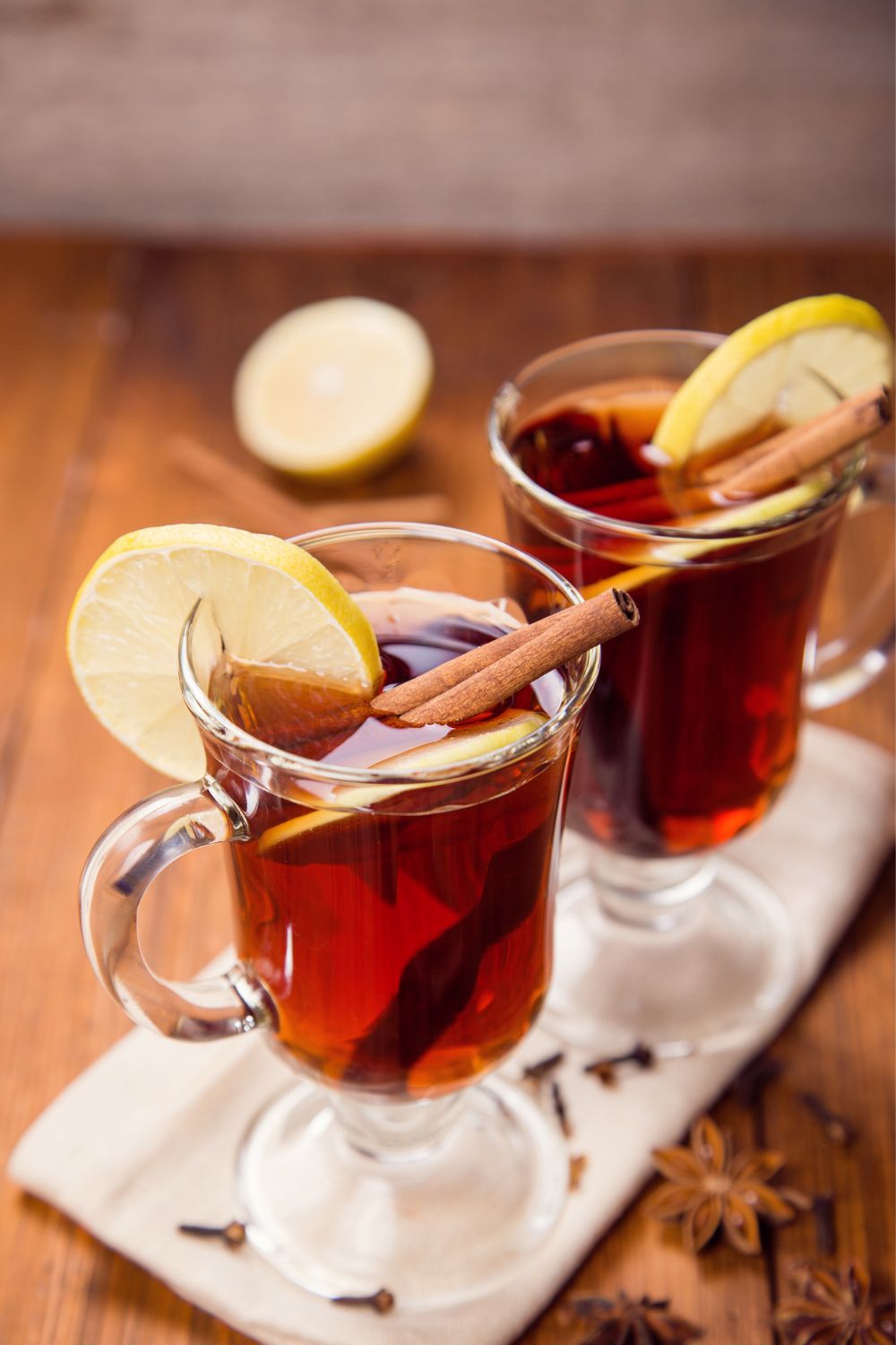 A hot coffee grog in a glass garnished with cinnamon stick and lemon.