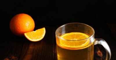 Spiked orange tea in a glass tea cup with orange.