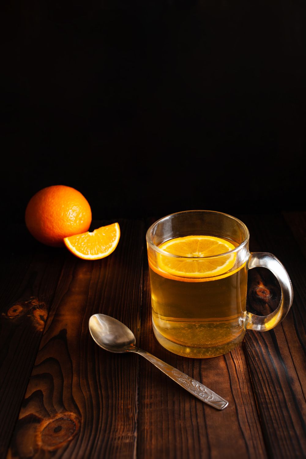 Spiked orange tea in a glass tea cup with orange.