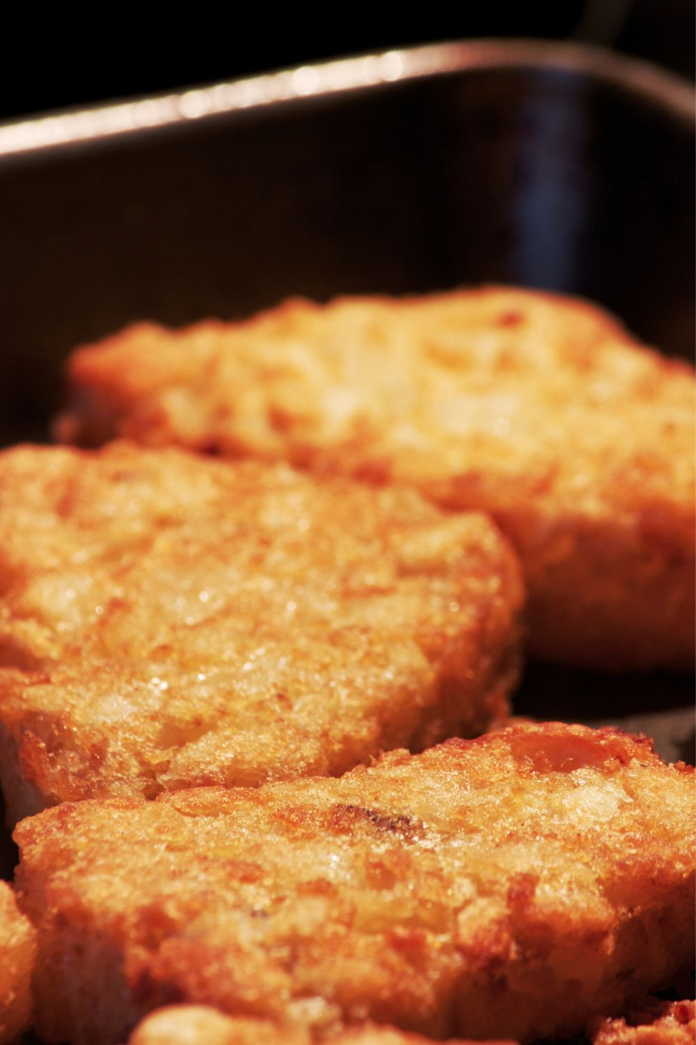 Three frozen hash browns being cooked in an air fryer