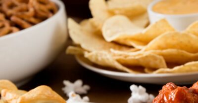 A bunch of appetizers on a table with a football in the background.