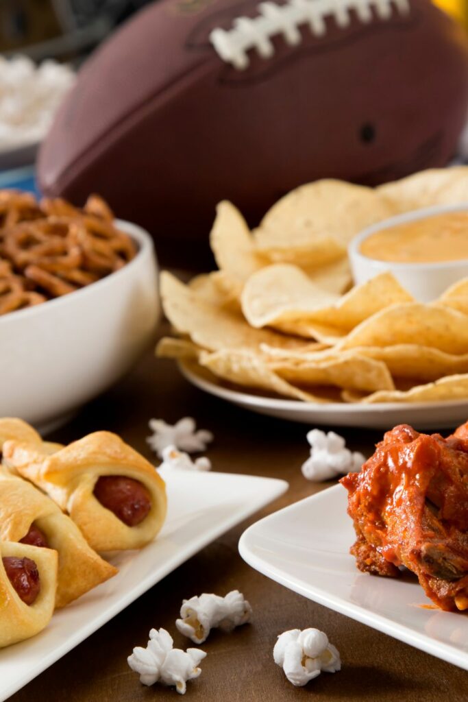 A bunch of appetizers on a table with a football in the background.