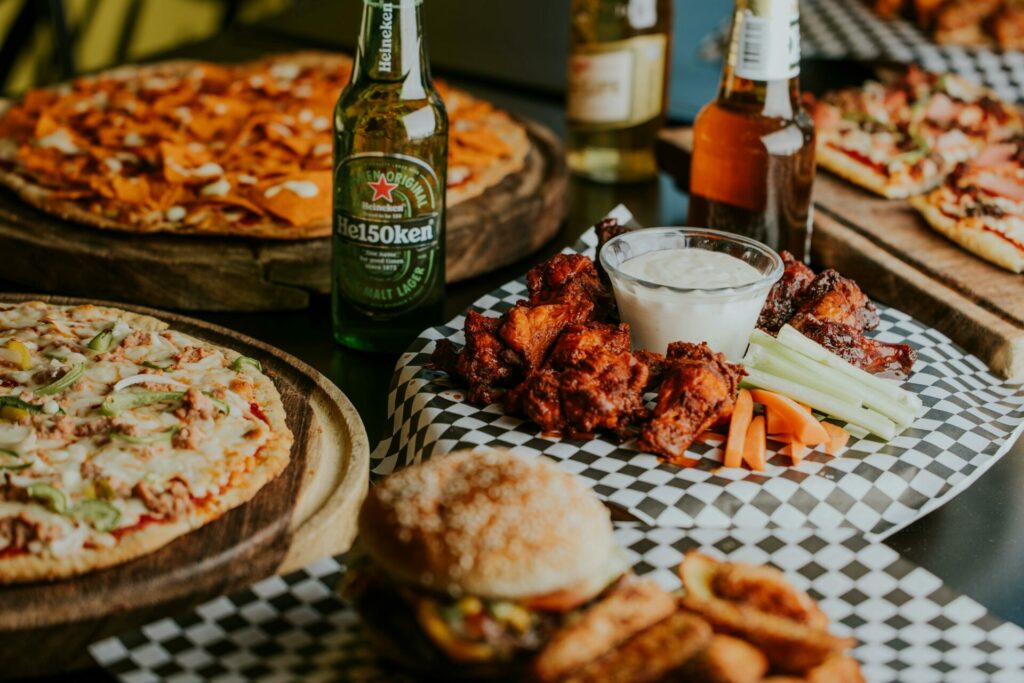 A spread of pizzas, wings, burgers and beer for a super bowl party.