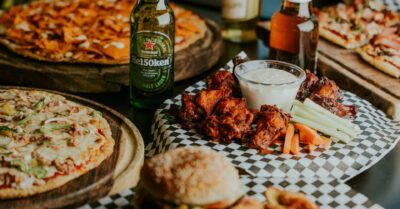 A spread of pizzas, wings, burgers and beer for a super bowl party.