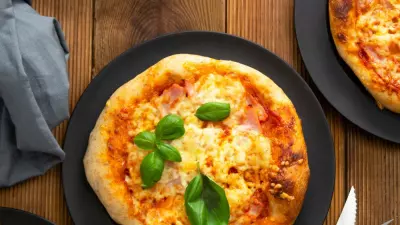 Overhead shot of grilled mini pizzas on black plates.