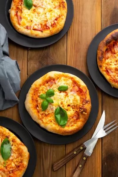 Overhead shot of grilled mini pizzas on black plates.