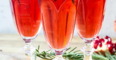 Three pomegranate mimosas in champagne flutes garnished with pomegranates and rosemary