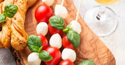 a wooden serving board with caprese salad skewers and breadsticks